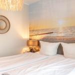 Schlafzimmer mit Bett, Wandbild und Lampe.