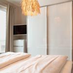 Schlafzimmer mit Bett, Schwebetüren-Schrank und Fenster zur Terrasse.