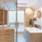 Badezimmer mit Whirlpool und Sauna im Hintergrund.
