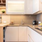 Küche mit Holzinsel, weißen Schränken und Küchenzeile mit Spüle und Kochfeld.