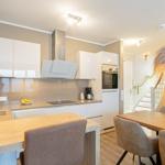 Küche mit Essbereich, Holztische und Stühle, weiße Schränke und integrierte Geräte.