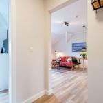 Wohnbereich mit rotem Sofa und Essplatz. Nebenraum mit Schrank und TV.