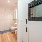 Badezimmer mit Dusche und Toilette, Küche mit Einbauherd.