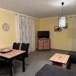 Wohn- und Essbereich mit Sofa, Esstisch, TV und Vorhängen.