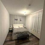 Schlafzimmer mit Bett, Nachttischen und Fenster mit Vorhängen.