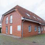 Rotes Backsteinhaus mit Dachfenstern und gepflastertem Hof.