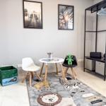 Kinderzimmer mit Tisch, Stühlen, Teppich und Kleiderständer.