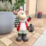 Weihnachtsreindeer mit Laterne und Tannenbaum steht auf Terrasse neben Pflanzen.