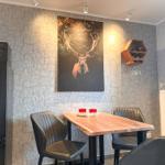 Essbereich mit Tisch, Stühlen und Wandbild eines Hirsches.