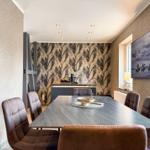 Esszimmer mit Tisch, Stühlen und Wandbild. Hintergrundwand mit Muster.