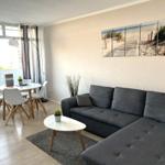 Wohnzimmer mit Sofa, Esstisch und Balkonansicht