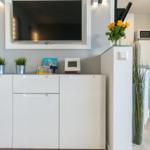 Wohnbereich mit Fernseher, weißen Schränken und Pflanzen.