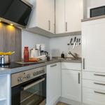 Küche mit weißen Schränken, Herd, Dunstabzug und Spüle.