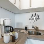 Küchenbereich mit Spüle, Kaffeemaschine und Messerblock an der Wand.
