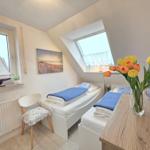 Room with two single beds, skylight, and window with sailboat model.