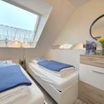 Two single beds under sloped ceilings with window and makeup table.