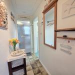 Hallway with mirror, wooden shelves, and seaside-themed wall decor.