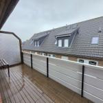 Terrace with wooden floor and bench. View of roof with skylights.