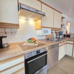 Kitchen with stove, sink, and microwave. Wooden surfaces and white cabinets.