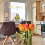 Kitchen and dining area with tulips, chairs, and window view.