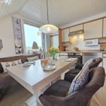 Dining area with table, bench, and kitchen. Window with sea motif.