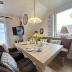 Dining room with wooden table, bench, and windows. Decorated with flowers and sailboats.