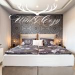 Schlafzimmer mit Doppelbett, gemusterter Wand und Nachttischen mit Lampen.