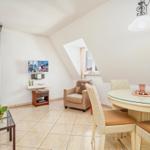 Wohn- und Essbereich mit Esstisch, Sessel und TV unter schrägen Dachdecken.