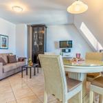 Wohn- und Essbereich mit Sofa, Esstisch und TV. Dachschrägen und Holzboden.