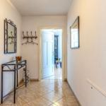 Flur mit Spiegel, Garderobe und Tisch. Tür führt in Wohnbereich.