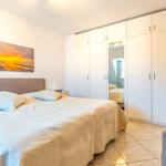 Schlafzimmer mit Doppelbett, Kleiderschrank und Wandbild.