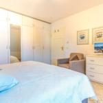 Schlafzimmer mit Bett, Kleiderschrank, Sessel und Schrank mit Fernseher.