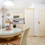 Esszimmer mit runden Tisch und Stühlen, Küche mit weißen Schränken und Fenster