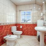 Badezimmer mit Toilette, Bidet, Waschbecken und Dusche. Rote und beige Fliesen.