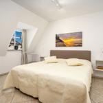 Schlafzimmer mit Dachfenster, Bett und Wandbild an der Wand.