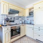 Küche mit cremefarbenen Schränken, Edelstahlherd und Mikrowelle.