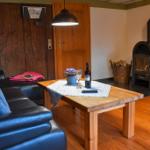 Ein Wohnzimmer mit Sofa, Tisch, Kaminofen und Holzboden.