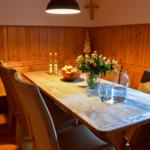 Holztisch mit Stühlen, Blumen und Obst an der Wand