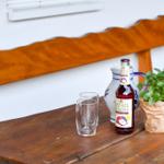 Holztisch mit Flasche, Gläsern und Pflanze im Freien.