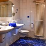 Badezimmer mit Dusche, Waschmaschine, zwei Waschbecken und Toilette.