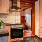 Küche mit Holzschränken, Edelstahlherd und Pflanze auf Arbeitsfläche.