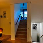 Treppenhaus mit Holztreppe und Vorhang. Im Hintergrund ist ein Ladder und ein Fenster sichtbar.