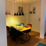 Esszimmer mit Holztisch, vier Stühlen und hängenden Lampen.