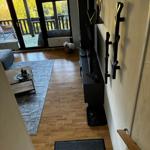 Wohnzimmer mit Holzboden, TV und Balkonzugang.