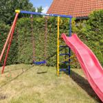 Kinder-Spielplatz mit Rutsche und Schaukel im Garten.