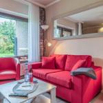 Ein Wohnzimmer mit rotem Sofa und Sessel, Tisch und Spiegel an der Wand.