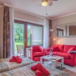 Zimmer mit rotem Sofa, Bett und Fenster zum Garten.