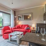 Wohnbereich mit rotem Sofa, Tisch und Blick auf Garten.