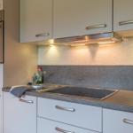 Küche mit Dunstabzugshaube, Spüle und integriertem Ofen.