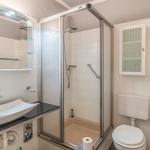 Badezimmer mit Dusche, Waschbecken und Toilette.